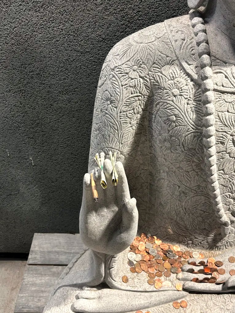 Stone Buddha statue hand holding pre-rolls outside Canna Buddha Hobbs